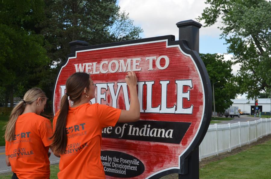 Girls painting Welcome to Poseyville sign